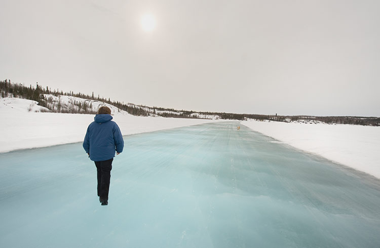 A woman walks on an ice road acoss a frozen lake in the Northwest Territories, Canada.