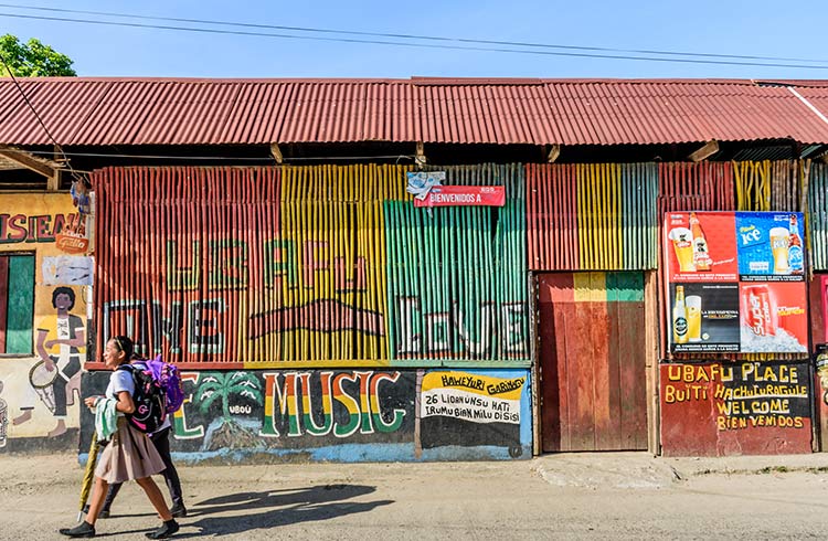 Girls walk past colorfully painted walls in street in Caribbean town of Livingston, Guatemala