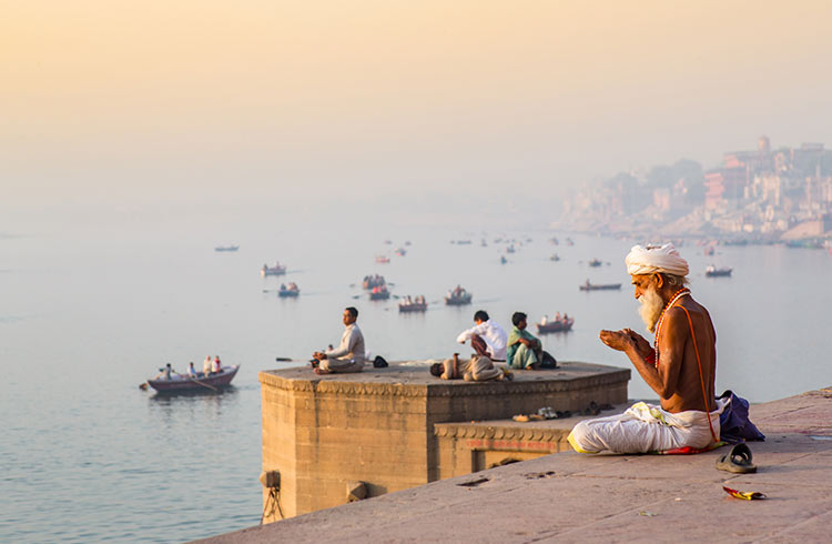 A Sadhu (Hindu religious devotee) doing morning prayer by the river Ganges in Varanasi, India