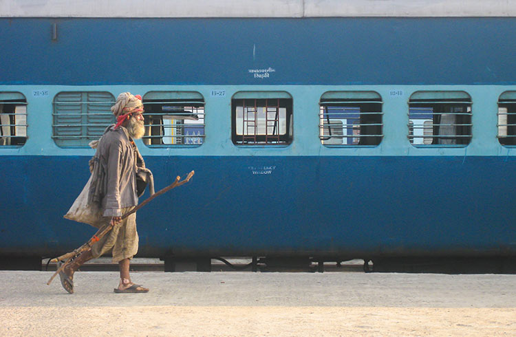 A local Indian man walks along a train platform in India. 