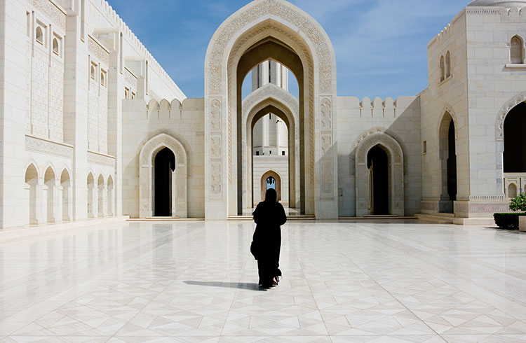 A woman walks through a temple complex in Oman.