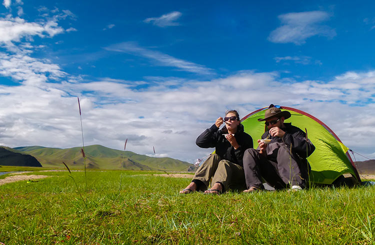 A couple camping on the steppe in Mongolia.
