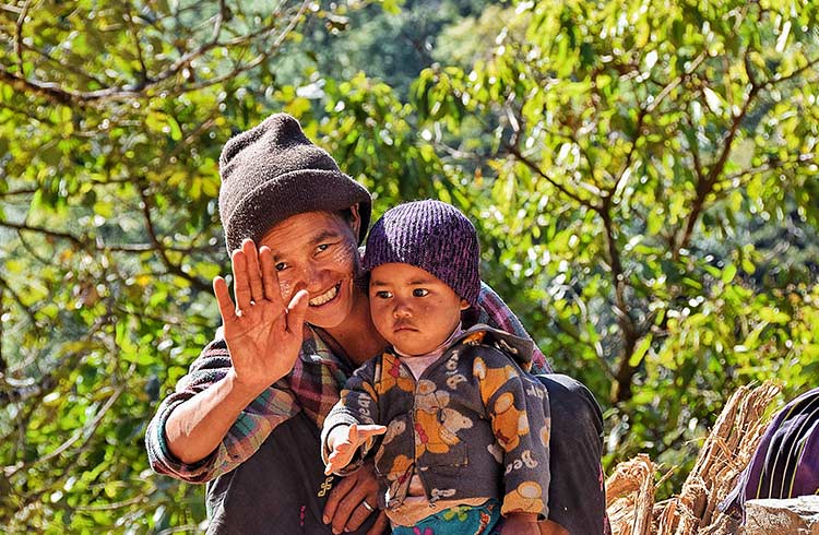 A parent holding a baby greets a traveler in Myanmar.