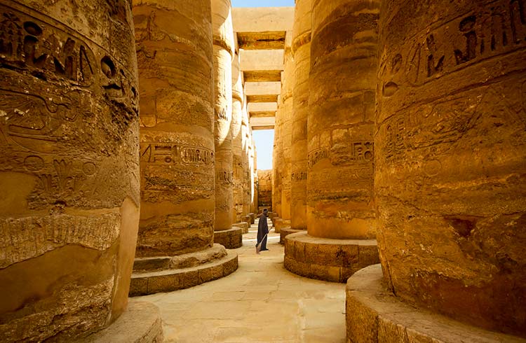 Walking between massive stone columns in the temple of Karnak in Egypt.