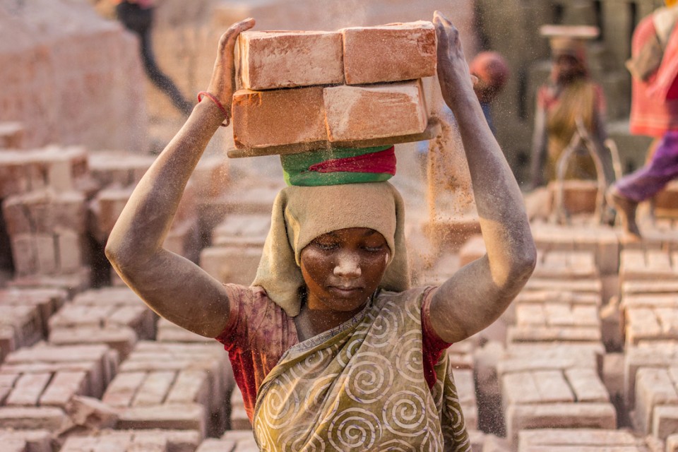 Woman carrying a large brick on her head