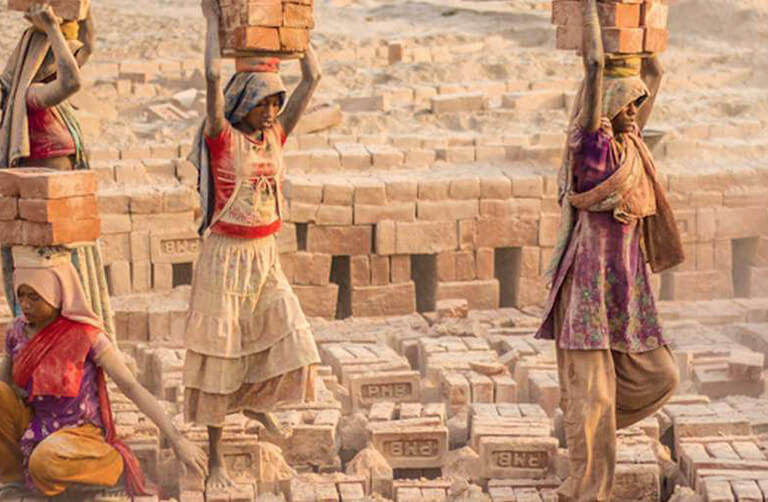 Indian girl carrying a large piece of brick