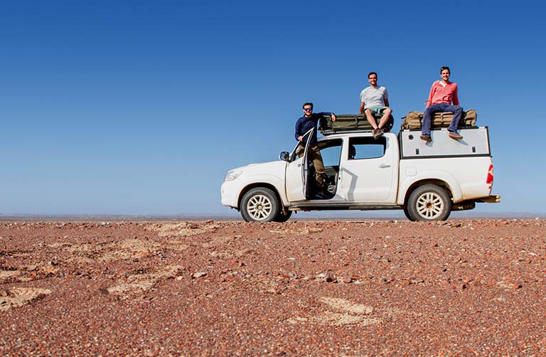 Three guys on a van in the desert