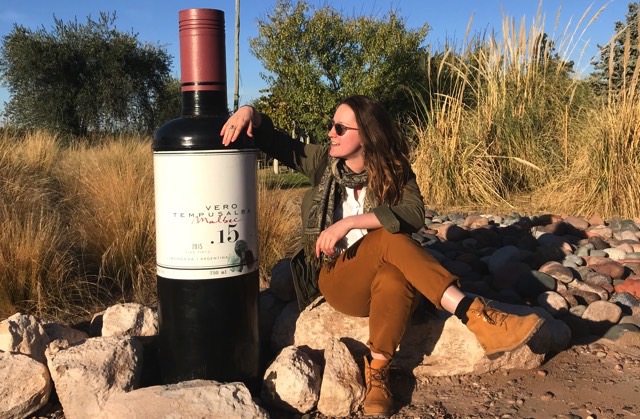 Claudia with a giant wine bottle in a vineyard