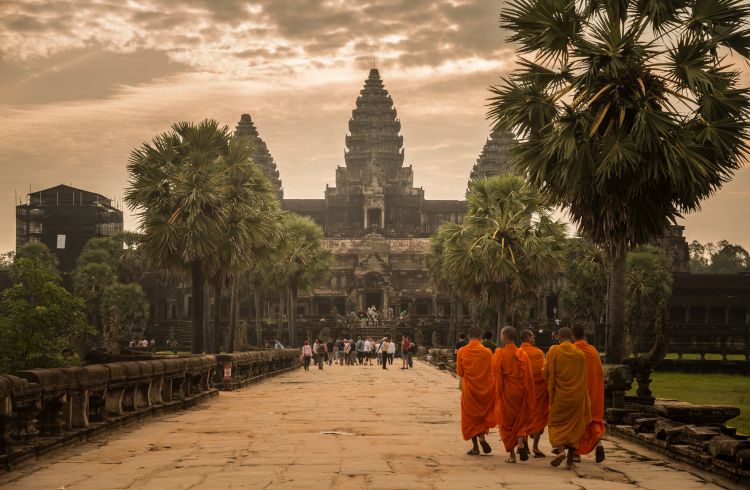 Angkor Wat at sunrise with monks walking