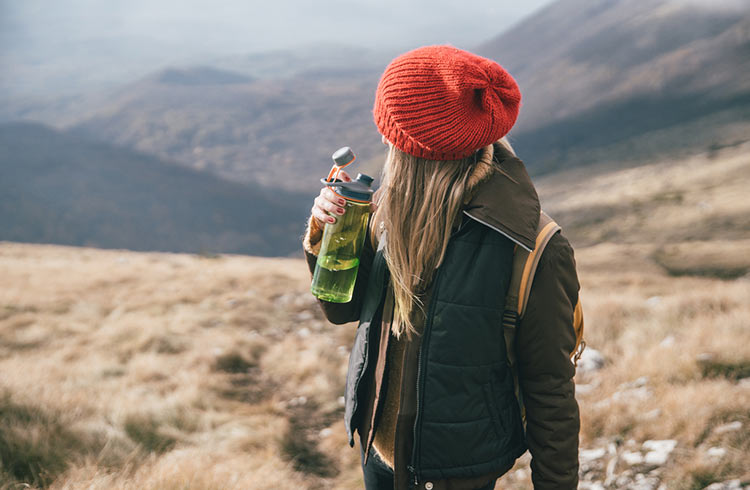 A hiker drinks from a reusable bottle