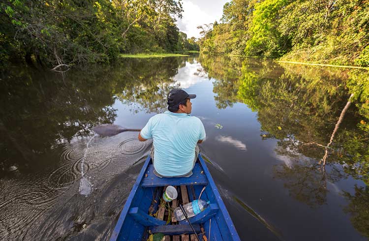 Jungle guide rowing in a canoe on the Yanayacu River near Iquitos, Peru