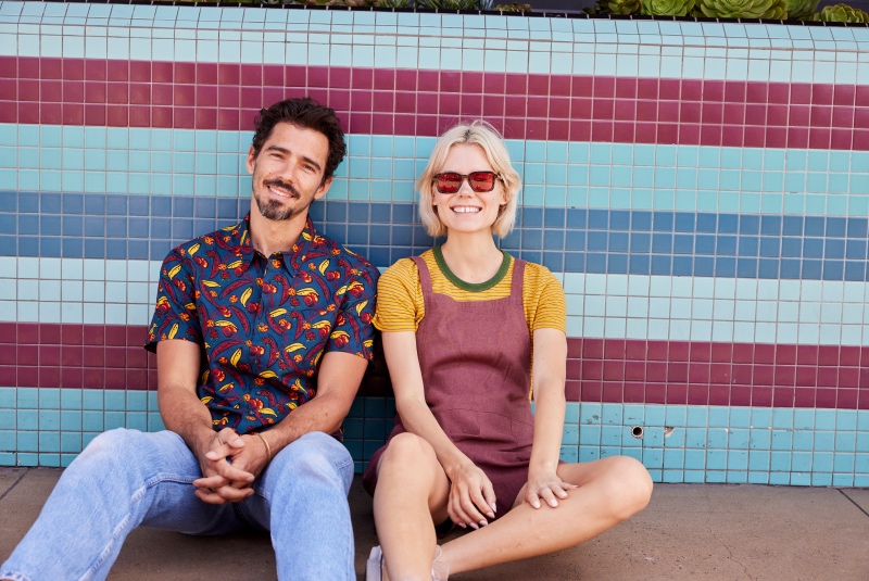 Two people in bright clothing sitting in front of a bright tiled wall
