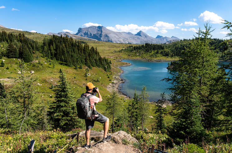 A hiker takes a photo of an alpine lake in Banff, Alberta.