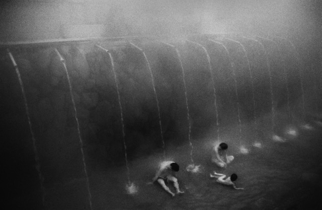 Three figures bathing under cascades
