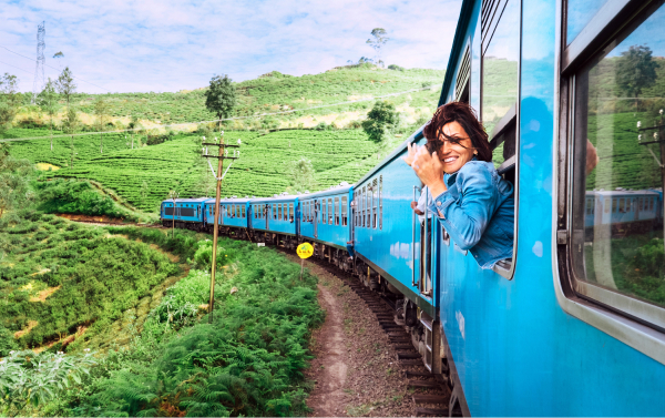 A woman looking out from a train window as the train drives through a field