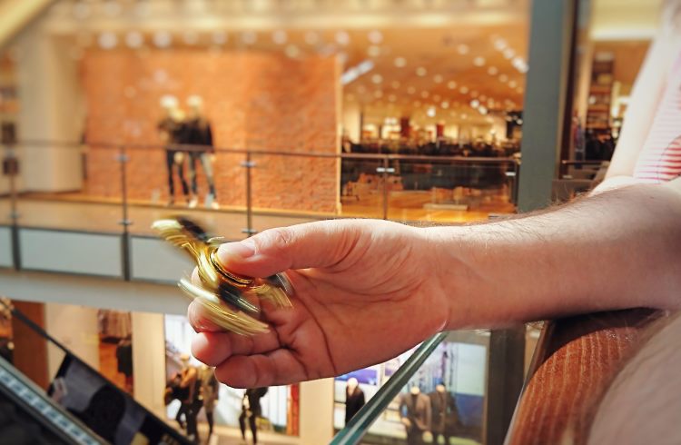 A man plays with a fidget spinner at a shopping mall.