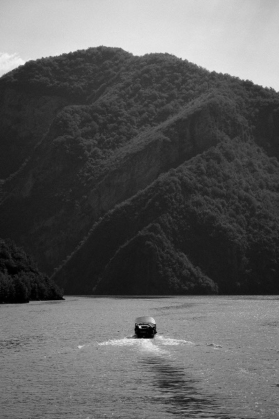 A boat driivng through water with a mountain visible in the background