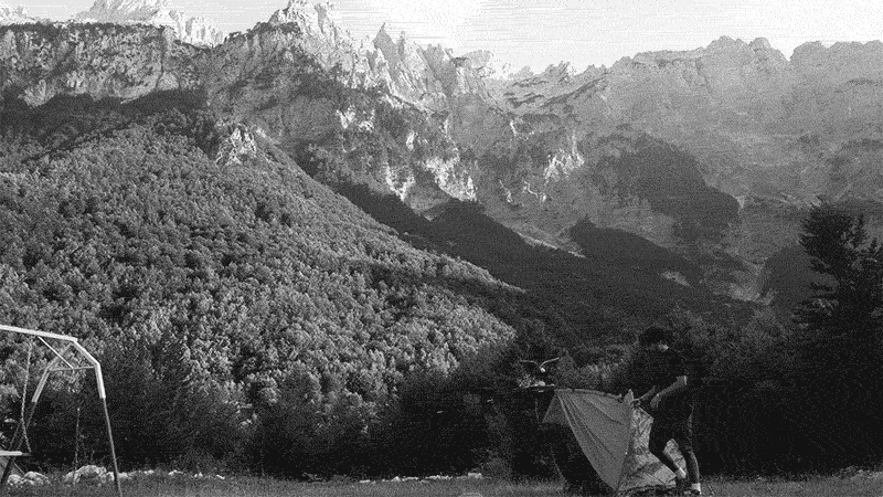 A short video of a person setting up a tent in front of Albanian mountains