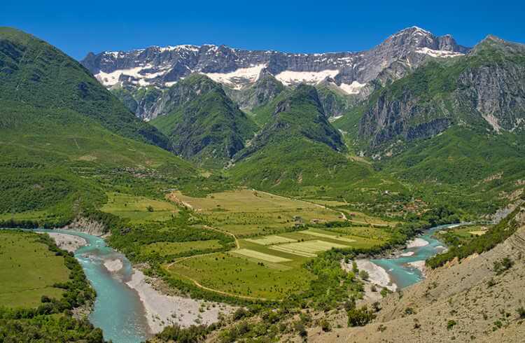 View of the Vjosa River near Kanikol, Albania, with snowcapped mountains in the background.
