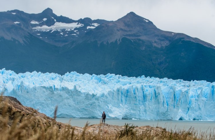 A traveler stands in front of massive Perito Moreno glacier in Argentine Patagonia.