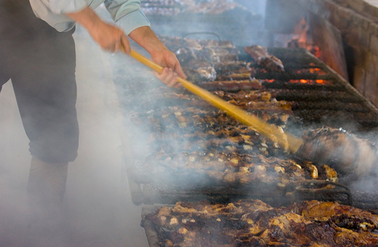 A gaucho man cooks ribs on a grill