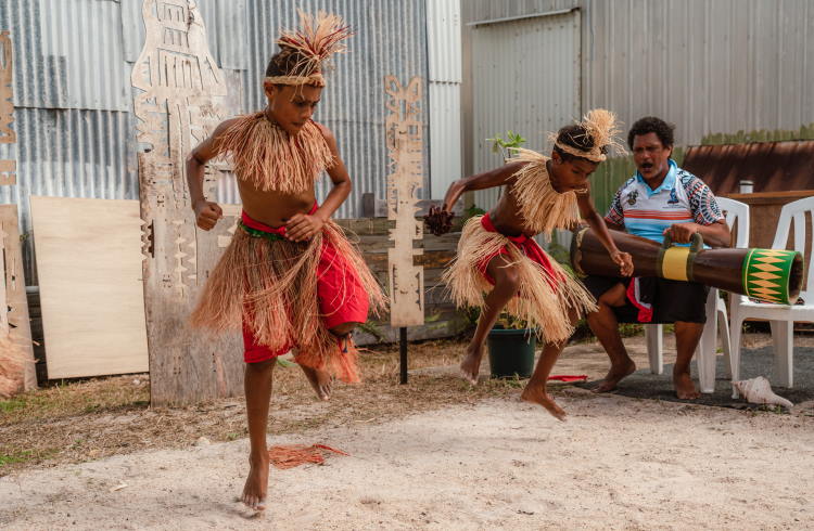 Young boys in grass skirts perform a traditional dance in the Torres Straits Islands.