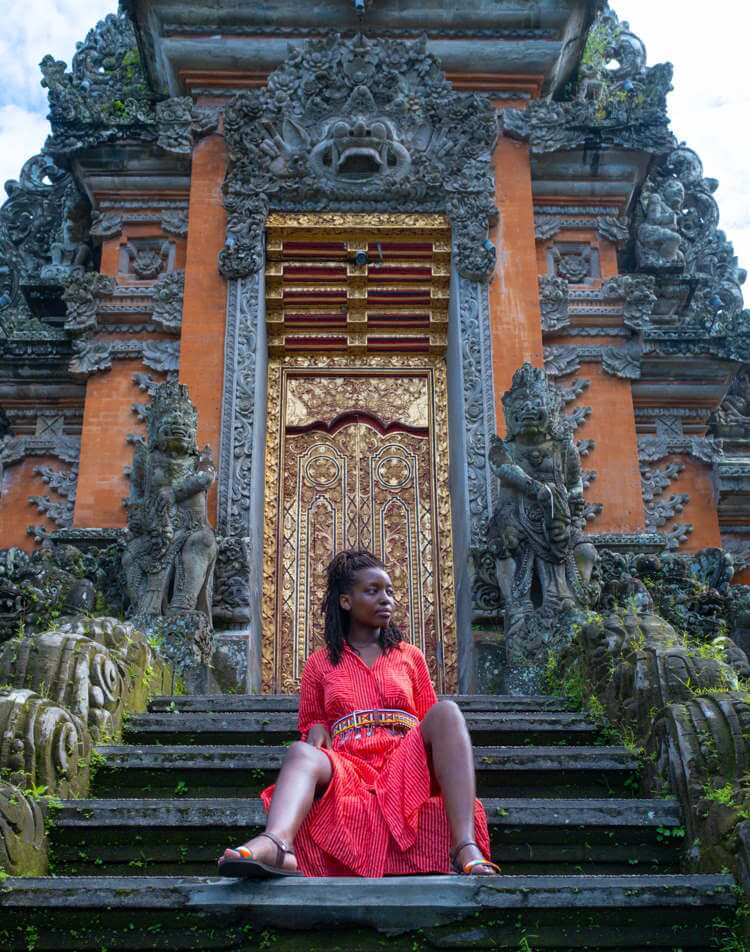 A woman sits on the steps in front of Saraswati Temple in Ubud, Bali.