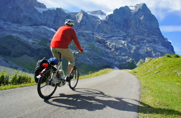 A man cycles along a car-free road in the Swiss Alps.