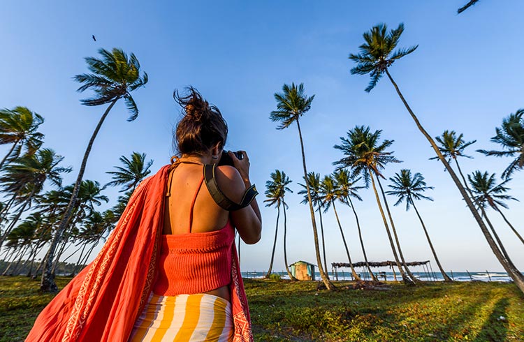 A woman taking photographs on a beach near Salvador, Brazil.