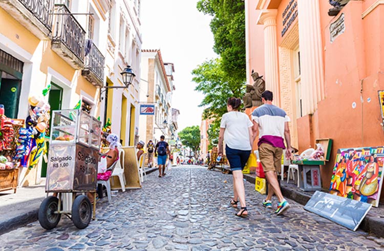 Visitors walk down a colorful street in Salvador, Brazil.