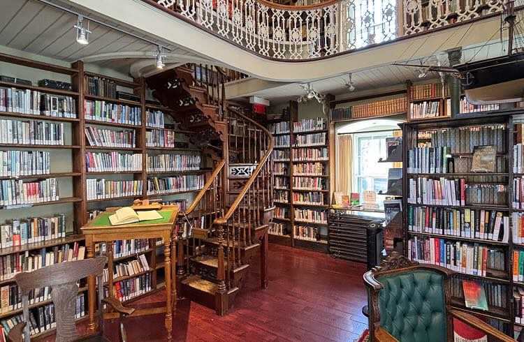 A winding staircase in a room filled with old books.