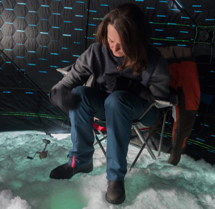 A woman ice fishes in a hut near Manitoulin Island, Ontario.