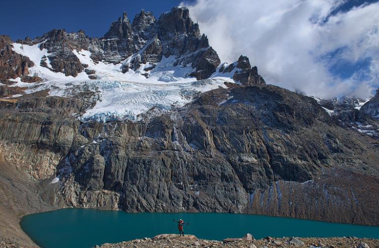 A hiker stands dwarfed by Cerro Castillo, a snow-covered massif in Patagonian Chile.