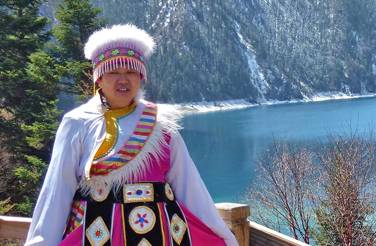 A woman wears brightly colored traditional clothing in Jiuzhaigou National Park