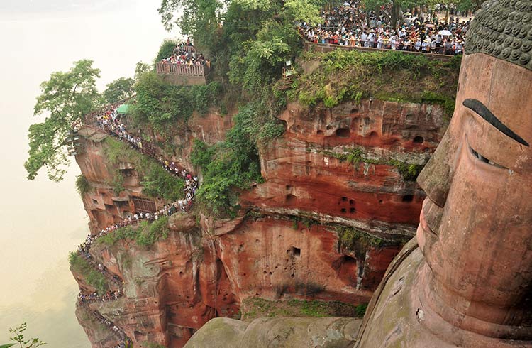 Huge lines of people on the stairs looking at the enormous statue of Buddha in Leshan