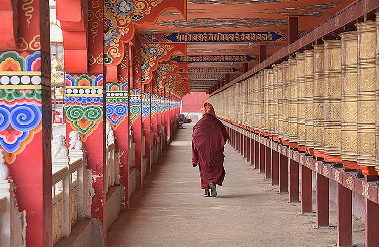 A monk walks through a religious building in Yarchen Gar