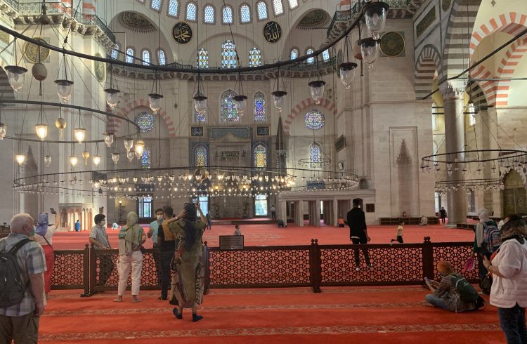 A handful of visitors, wearing face masks, inside the ornate Sulimaniye Mosque in Istanbul.