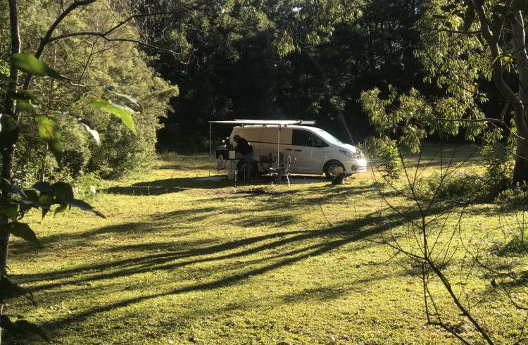A campervan parked in a large, green field in New South Wales, Australia.