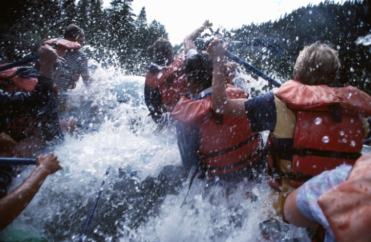A group of people paddle a raft through a white-water rapid on the Snake River in the northwest US.