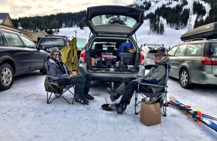 Two men enjoy a tailgate picnic in the parking lot of the Mount Bachelor ski area.