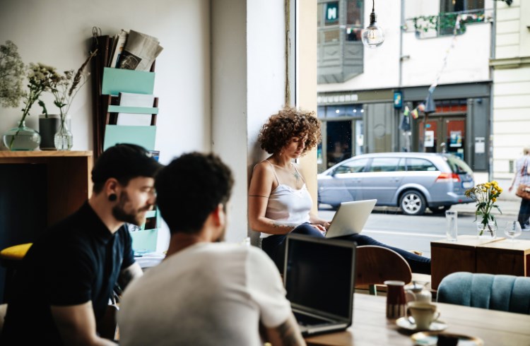 A trio of young travelers work on laptops in a cafe in Berlin.