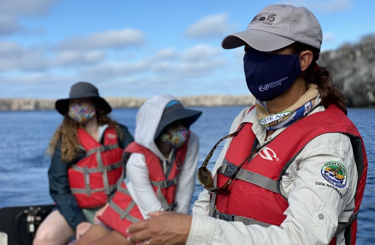 A naturalist guide wearing a face mask aboard a nature tour boat in the Galapagos.