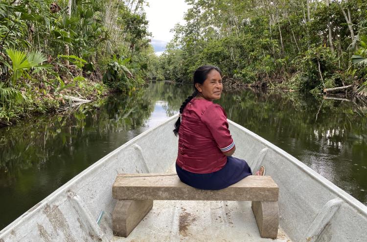A Quechua woman sits aboard a canoe on a river in the Ecuadorian Amazon.