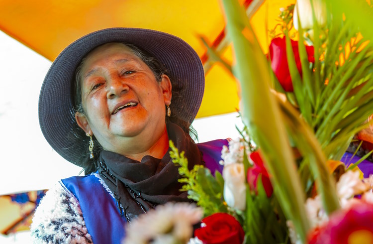An Andean woman in traditional clothing sells flowers at a market in Cuenca, Ecuador.