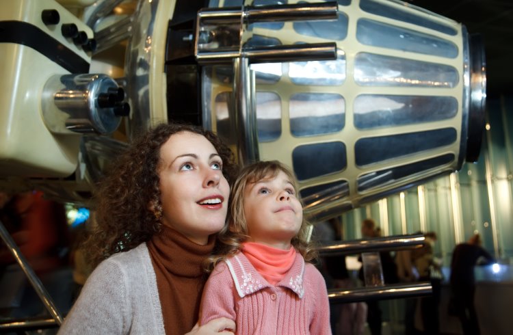 A mother and daughter look at exhibits at an aeronautics museum.