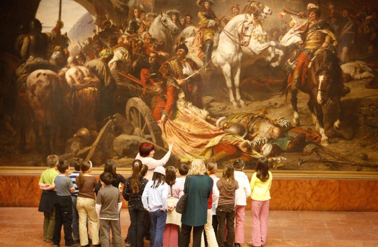 A tour guide points out a detail in a large painting at the Budapest History Museum