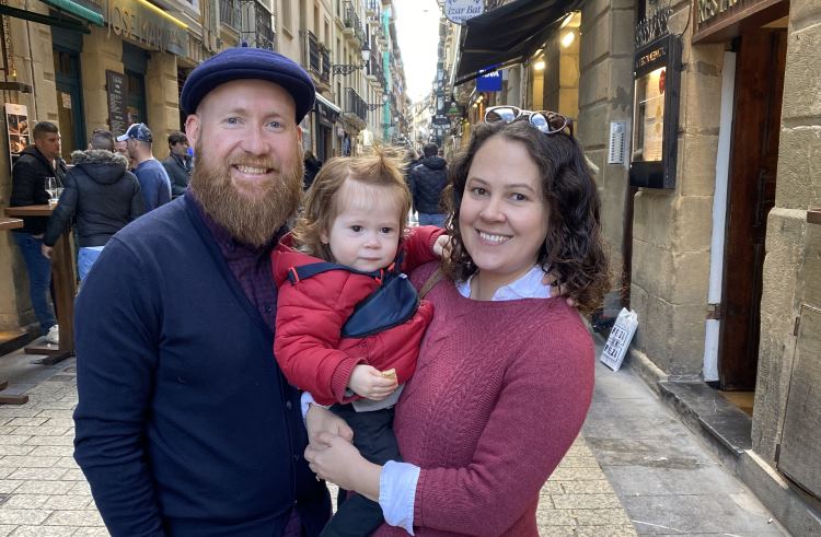 A father, mother, and toddler-aged son stand in a narrow lane in San Sebastian, Spain.