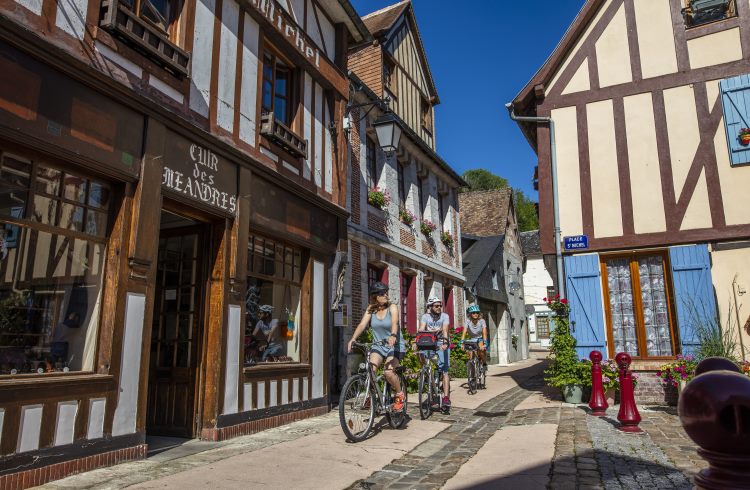 Bicyclists pedal past half-timbered houses in the French village of La Bouille.