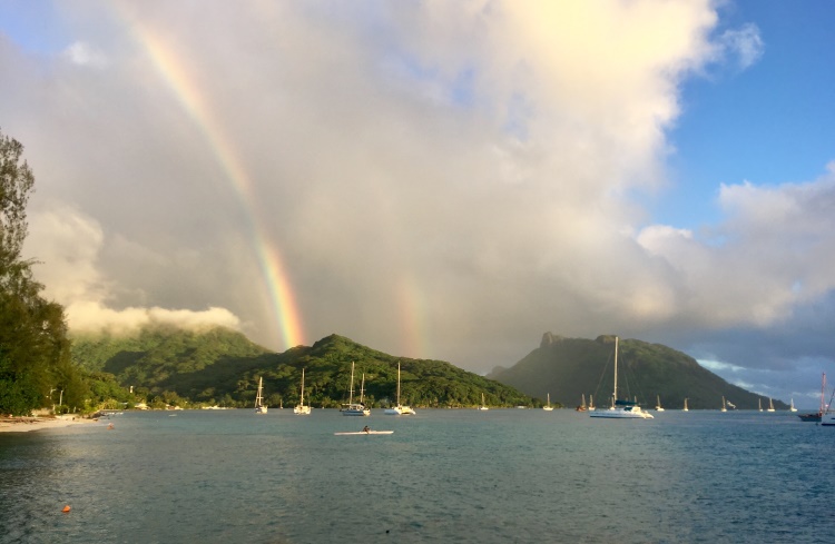 A rainbow arches over a turquoise bay on the island of Huahine, French Polynesia.