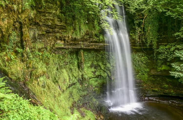 Glencar waterfall cascades down a lush green hillside in Leitrim, Ireland.